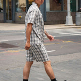 Man wearing a monotone plaid button-up shirt and shorts walking on the street, showcasing a modern casual look.