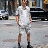 Monotone plaid button-up shirt styled in a relaxed fit, paired with matching shorts on city street.