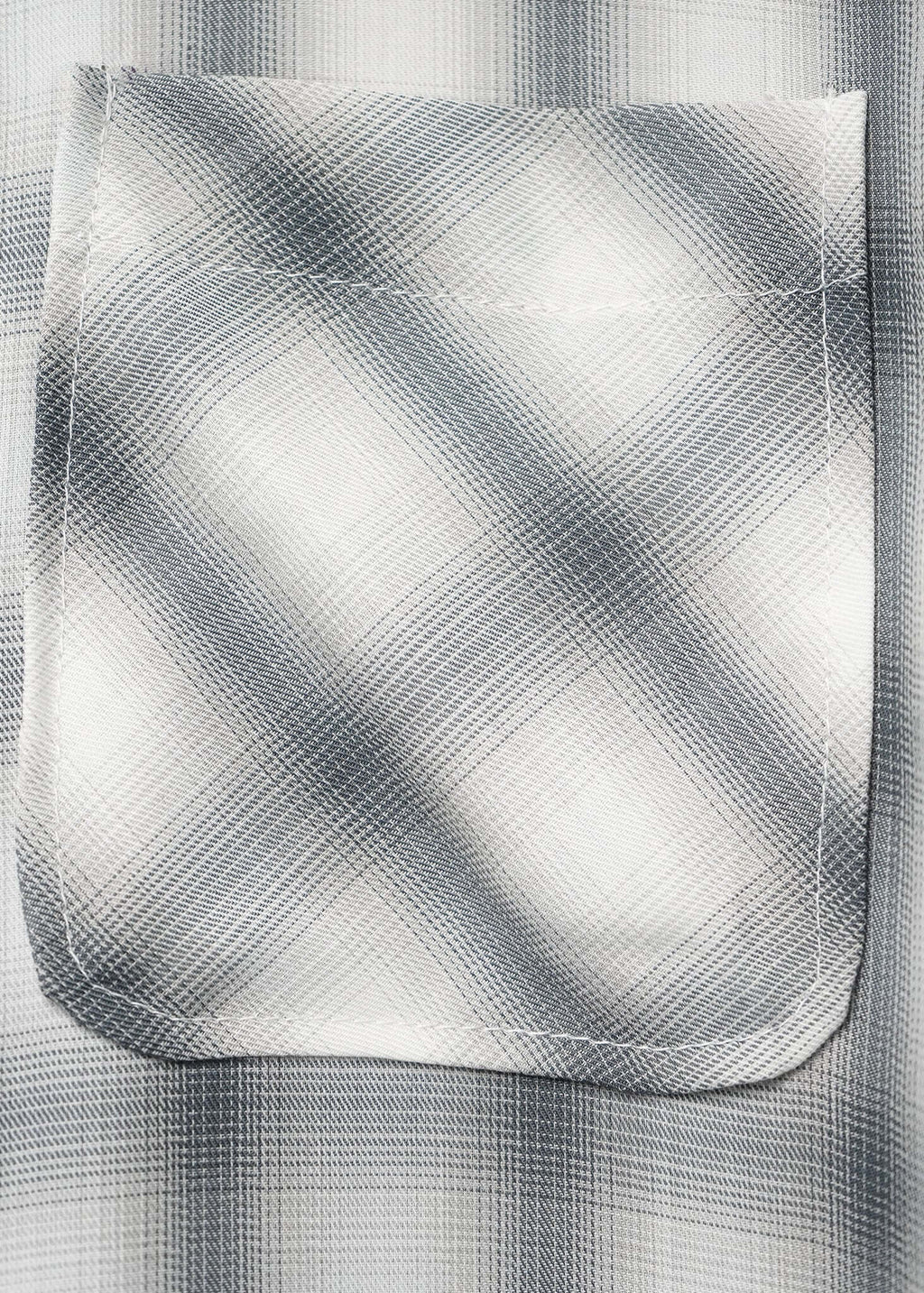 Close-up of the pocket on a monotone plaid button-up shirt showcasing its texture and design details.