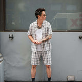 Person wearing a monotone plaid button-up shirt with matching shorts, styled casually in an urban setting.