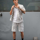Model wearing a monotone plaid button-up shirt with matching shorts, showcasing a modern and relaxed style.