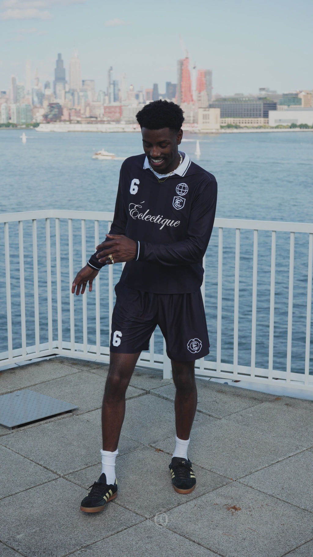 Model wearing performance soccer shorts by Éclectique near waterfront with city skyline in background