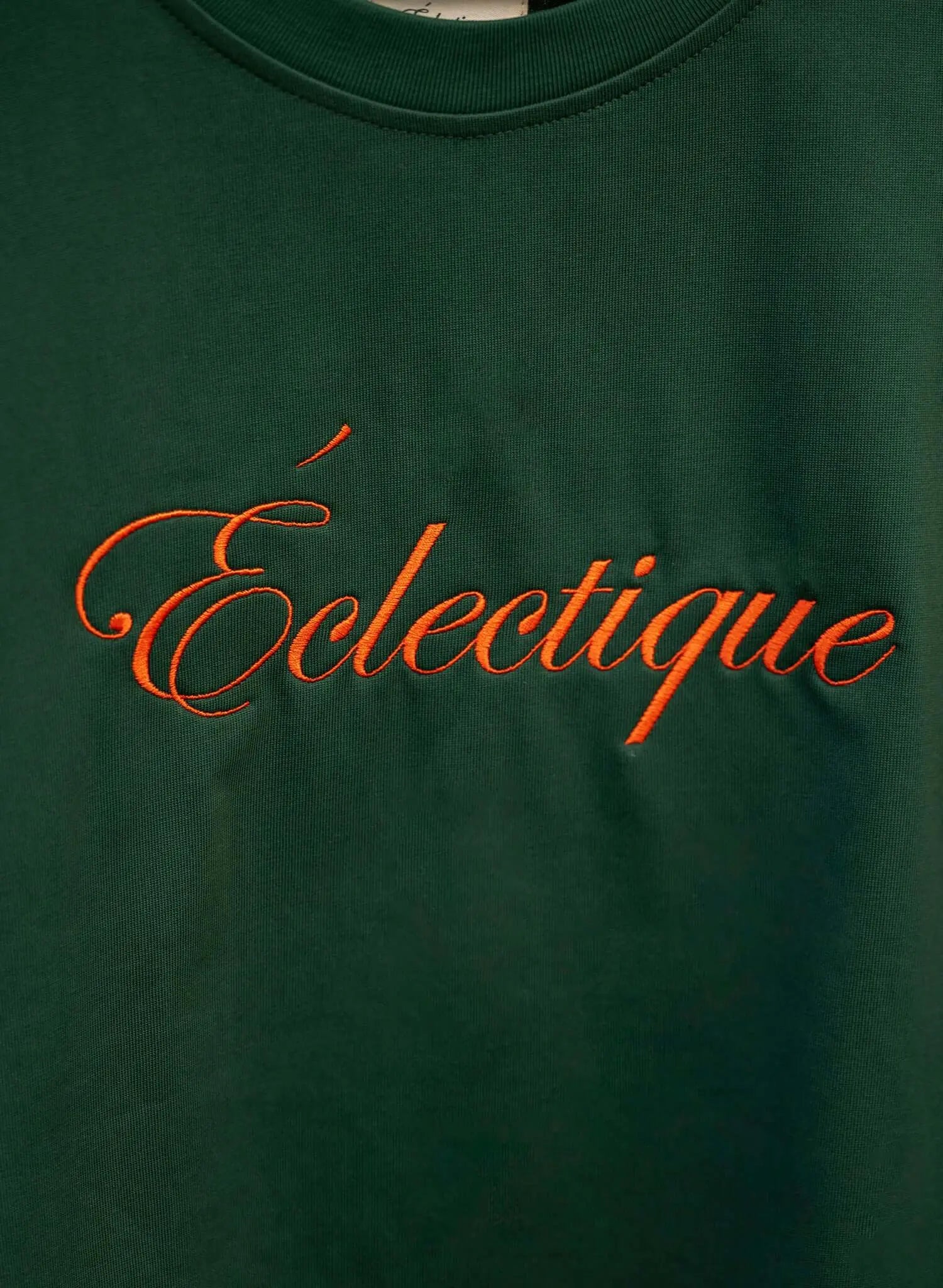 Script logo embroidered cotton t-shirt featuring Éclectique in orange on emerald fabric.