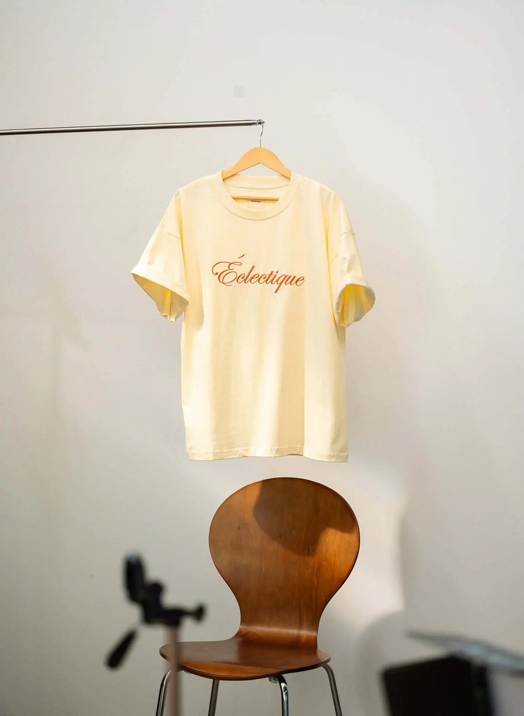 Script logo embroidered cotton t-shirt in French vanilla hanging on a rack, showcasing casual style.