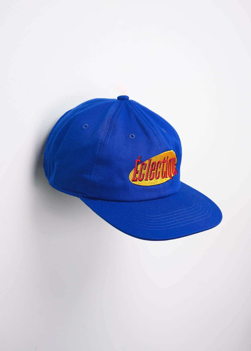 Seinfeld vintage logo hat in royal blue with embroidered Éclectique logo on the front, showcasing a vintage style.