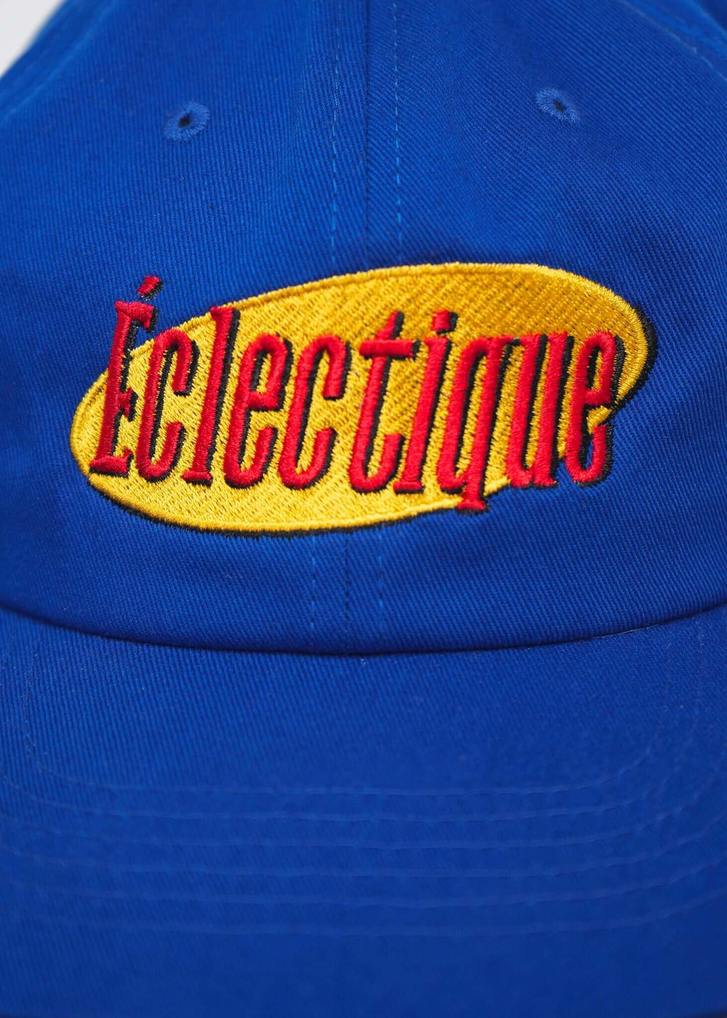 Close-up of the Éclectique embroidered logo on a royal blue Seinfeld vintage logo hat.