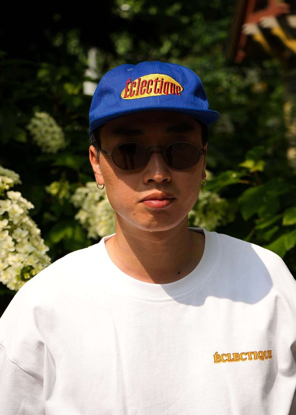 Man wearing a Seinfeld vintage logo hat in royal blue, with sunglasses and an Éclectique t-shirt.
