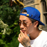 Man wearing a Seinfeld Vintage Logo Hat, sunglasses, and a white tee, showcasing a casual summer look.