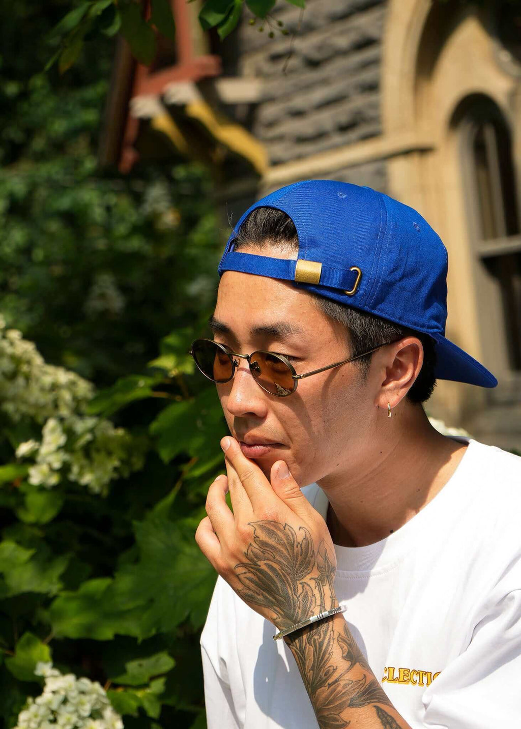 Man wearing a Seinfeld vintage logo hat, sunglasses, and a white tee, showcasing a casual summer look.