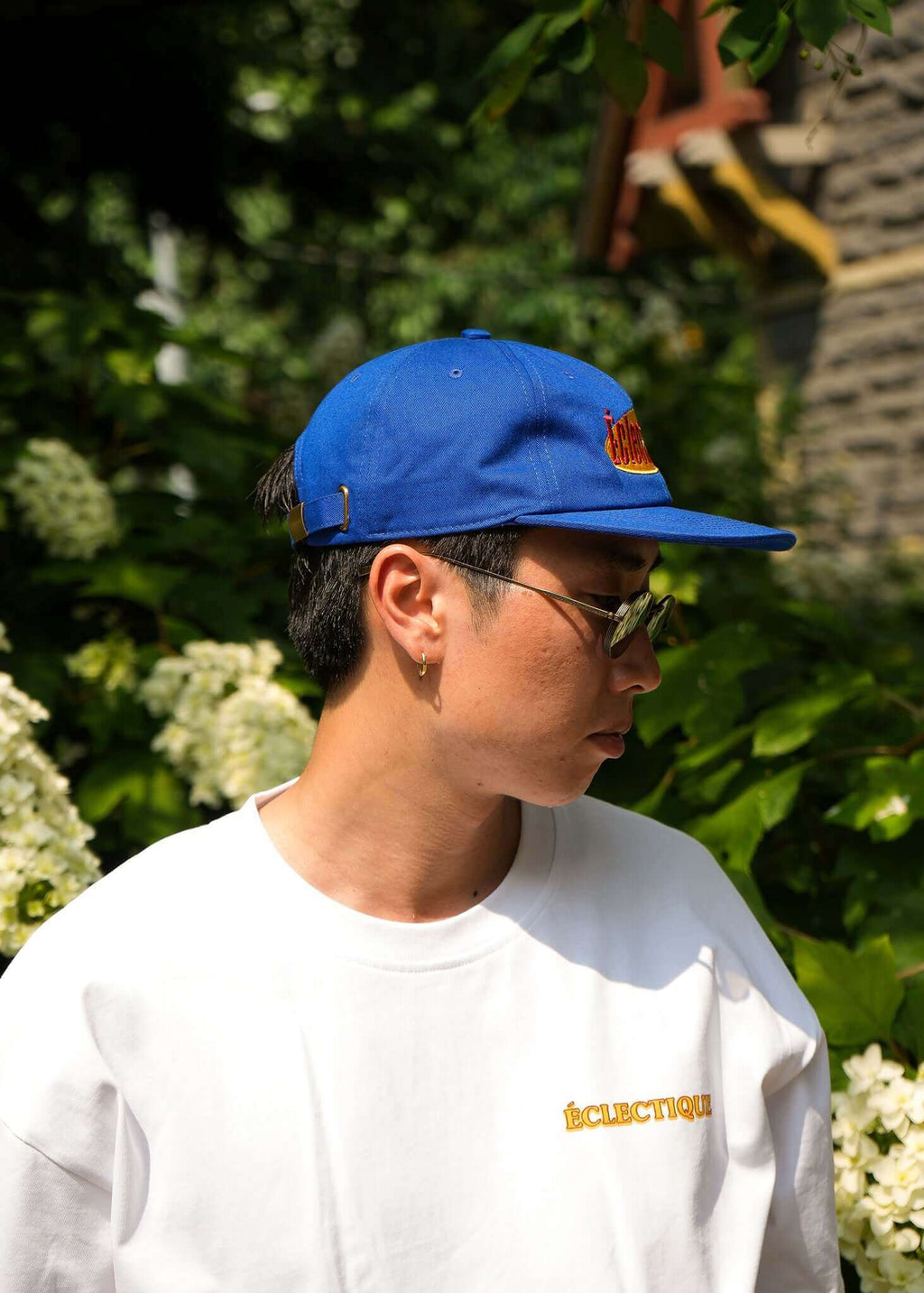 Seinfeld vintage logo hat worn by a person, featuring a royal blue color and embroidered logo against a green background.
