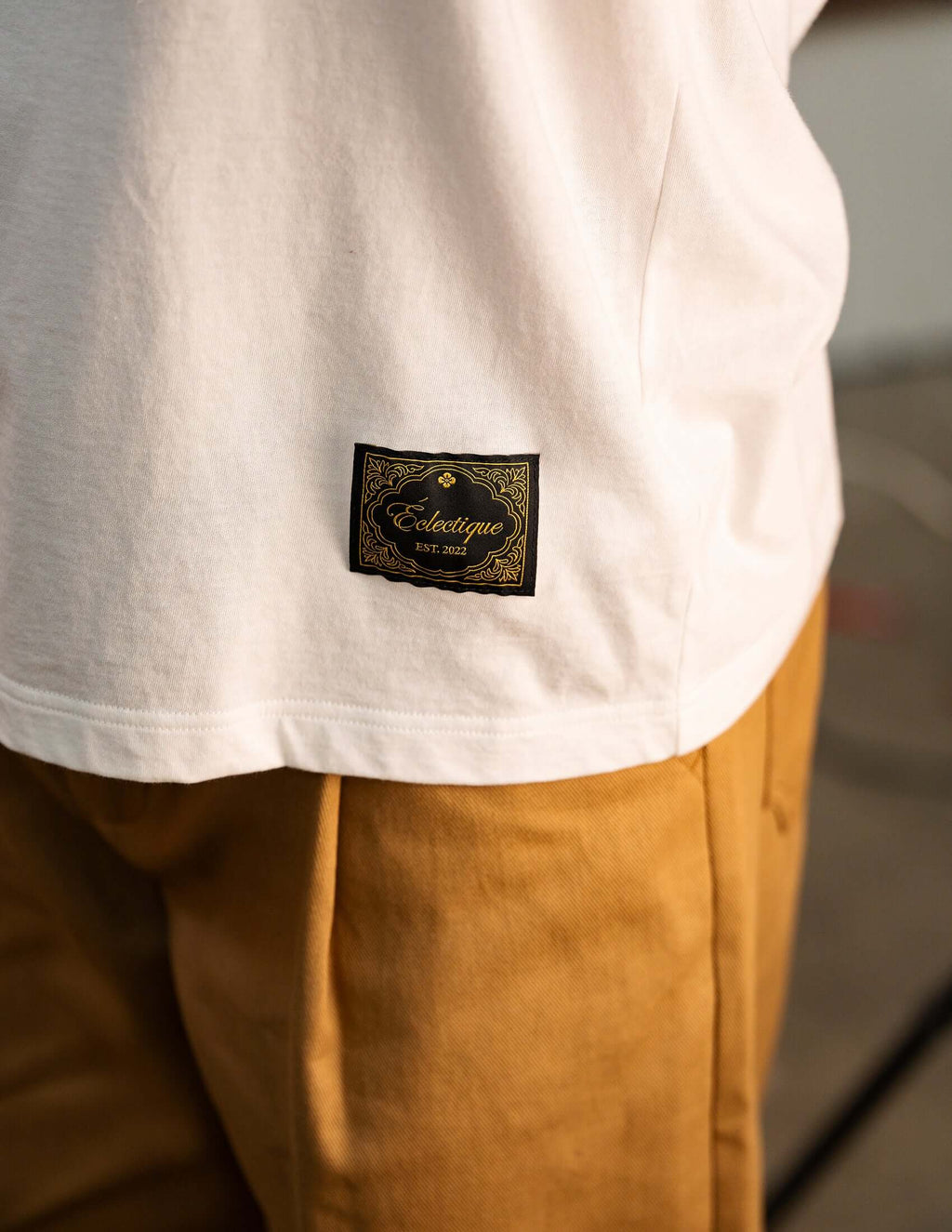 Men's White Cotton T-shirt showcasing Éclectique label stitched on the hem.